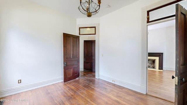 spare room with a notable chandelier and wood-type flooring