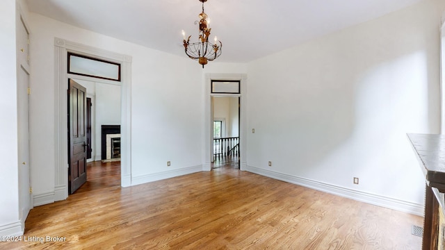 empty room with light hardwood / wood-style flooring and an inviting chandelier