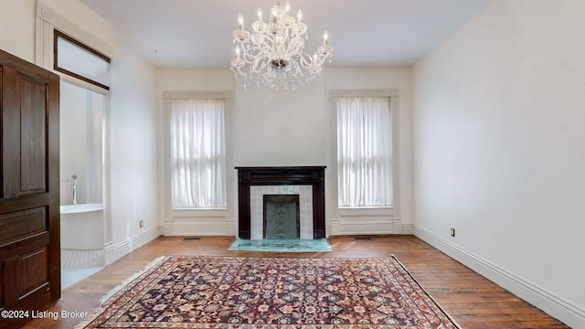 unfurnished living room featuring plenty of natural light, light hardwood / wood-style flooring, and a chandelier