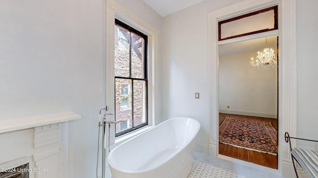 bathroom featuring tile patterned floors, a bath, and an inviting chandelier