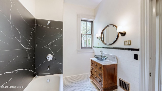 bathroom featuring tile patterned flooring, vanity, tile walls, and a bathing tub