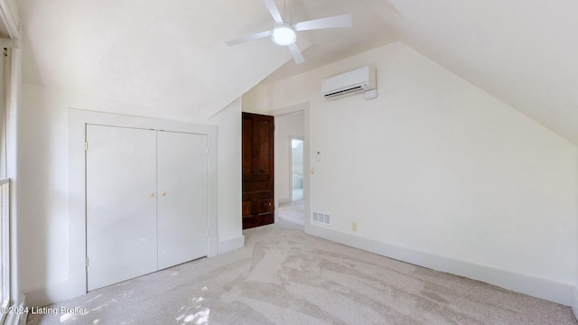 unfurnished bedroom with vaulted ceiling, ceiling fan, light colored carpet, a wall unit AC, and a closet