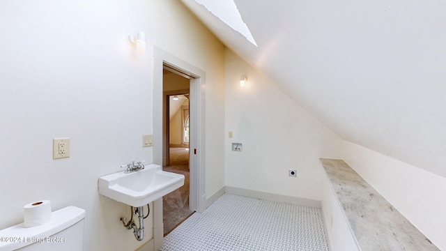 bathroom with vaulted ceiling with skylight, toilet, and tile patterned floors