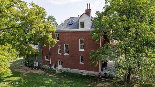 rear view of house with central air condition unit and a lawn