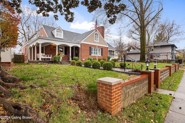 cape cod-style house featuring a front yard and covered porch