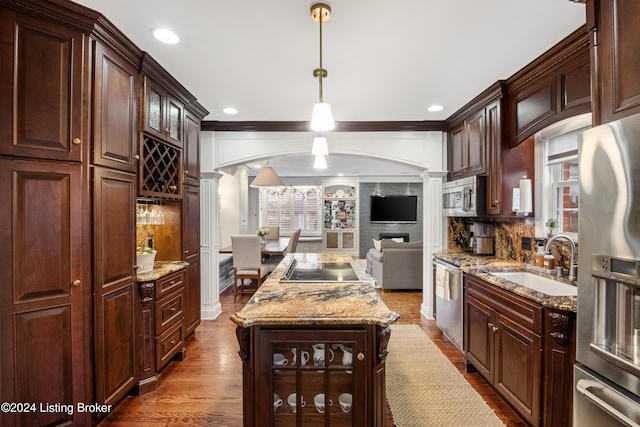 kitchen with appliances with stainless steel finishes, hanging light fixtures, decorative columns, and sink