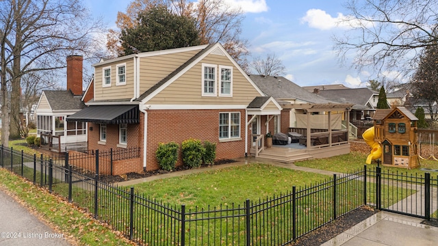 rear view of house featuring a wooden deck, a playground, a sunroom, and a lawn