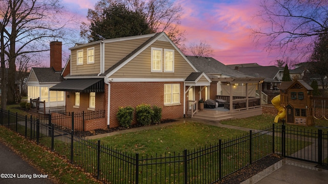 back house at dusk featuring a lawn