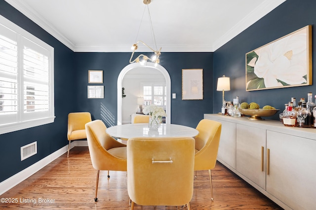 dining area with light wood-type flooring and crown molding