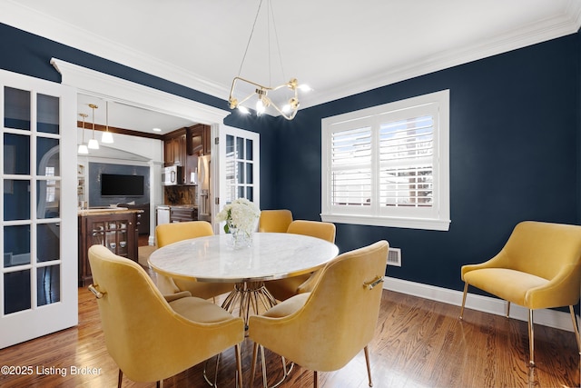 dining area with vaulted ceiling, crown molding, and wood-type flooring