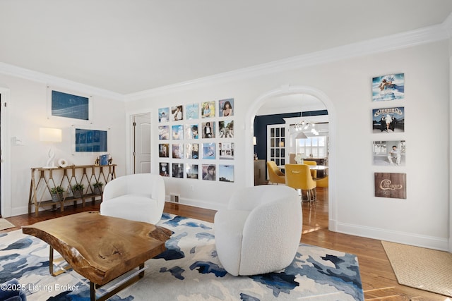 living room with an inviting chandelier, crown molding, and hardwood / wood-style floors