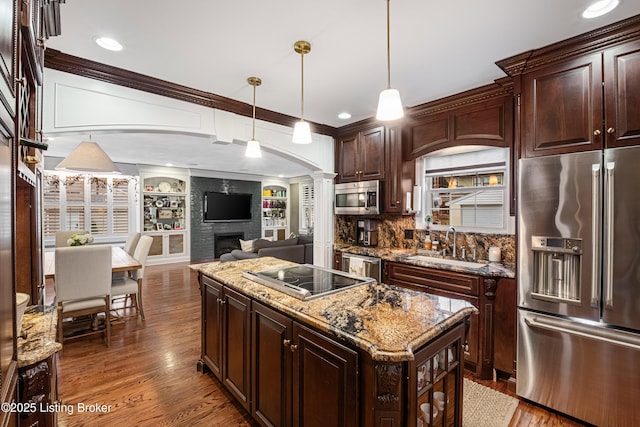 kitchen featuring a center island, built in features, hanging light fixtures, dark brown cabinets, and appliances with stainless steel finishes