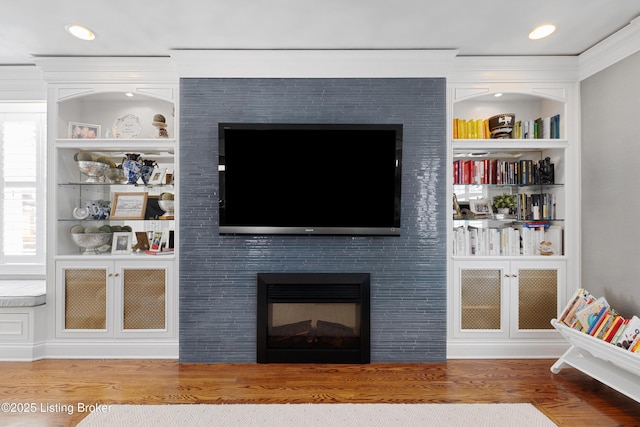 living room featuring a tile fireplace, hardwood / wood-style flooring, and built in features