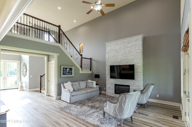 living room with ceiling fan, a fireplace, high vaulted ceiling, and light hardwood / wood-style floors