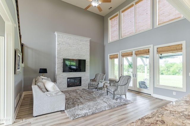 living room featuring a fireplace, ceiling fan, light hardwood / wood-style flooring, and a healthy amount of sunlight