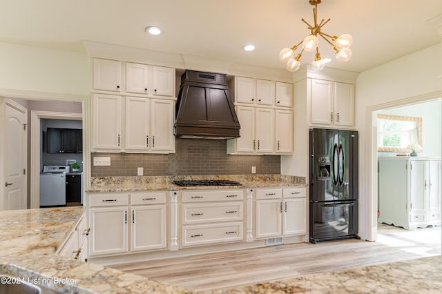 kitchen with fridge with ice dispenser, light hardwood / wood-style flooring, premium range hood, washer / clothes dryer, and stainless steel gas stovetop