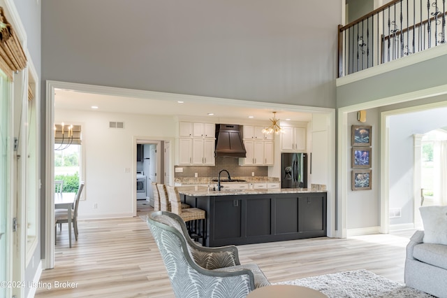 living room with plenty of natural light, a towering ceiling, an inviting chandelier, and light hardwood / wood-style flooring