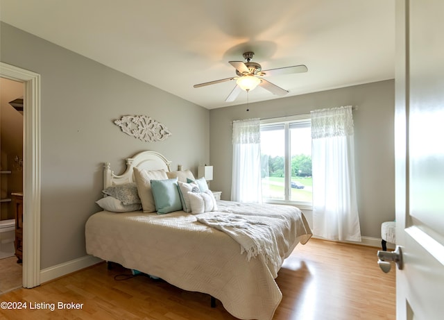 bedroom featuring ceiling fan, light hardwood / wood-style floors, and ensuite bath