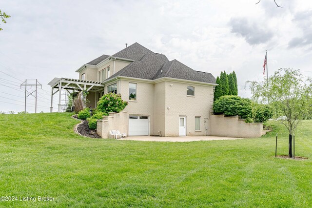 back of house with a garage, a pergola, and a yard