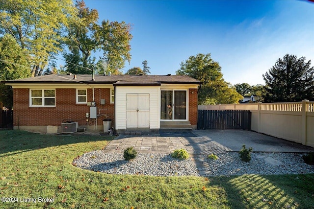 rear view of house featuring a patio, central AC, and a lawn