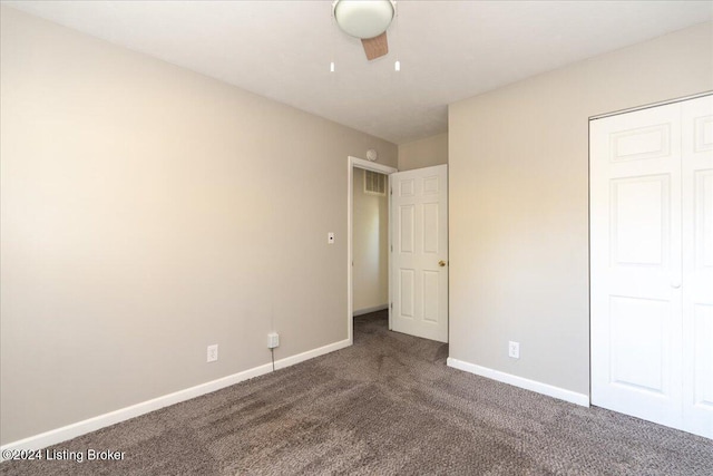 unfurnished bedroom featuring ceiling fan, dark carpet, and a closet