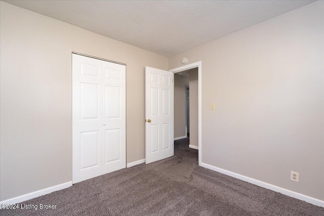 unfurnished bedroom featuring dark carpet and a closet