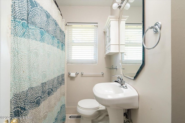 bathroom featuring tile patterned floors, toilet, plenty of natural light, and sink