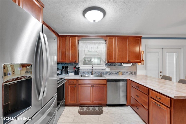 kitchen featuring sink, stainless steel appliances, kitchen peninsula, and a textured ceiling