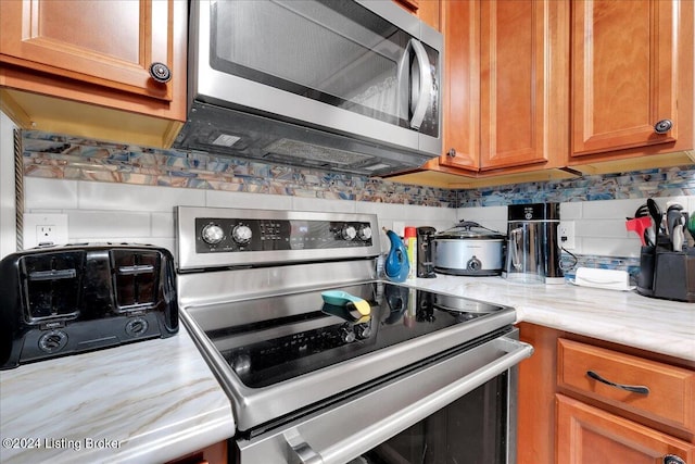 kitchen featuring light stone countertops, appliances with stainless steel finishes, and decorative backsplash