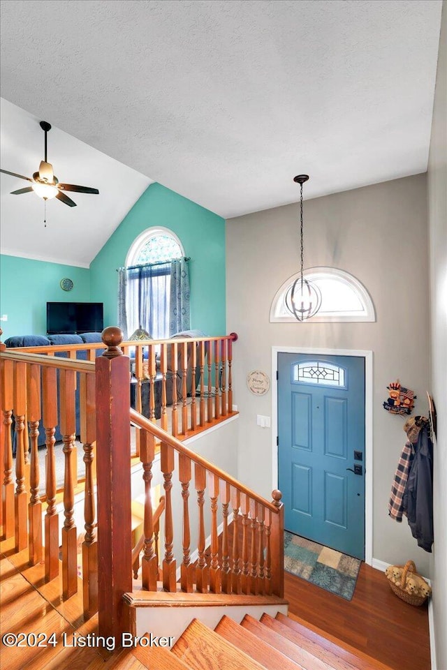 entrance foyer with hardwood / wood-style flooring, ceiling fan, vaulted ceiling, and a textured ceiling