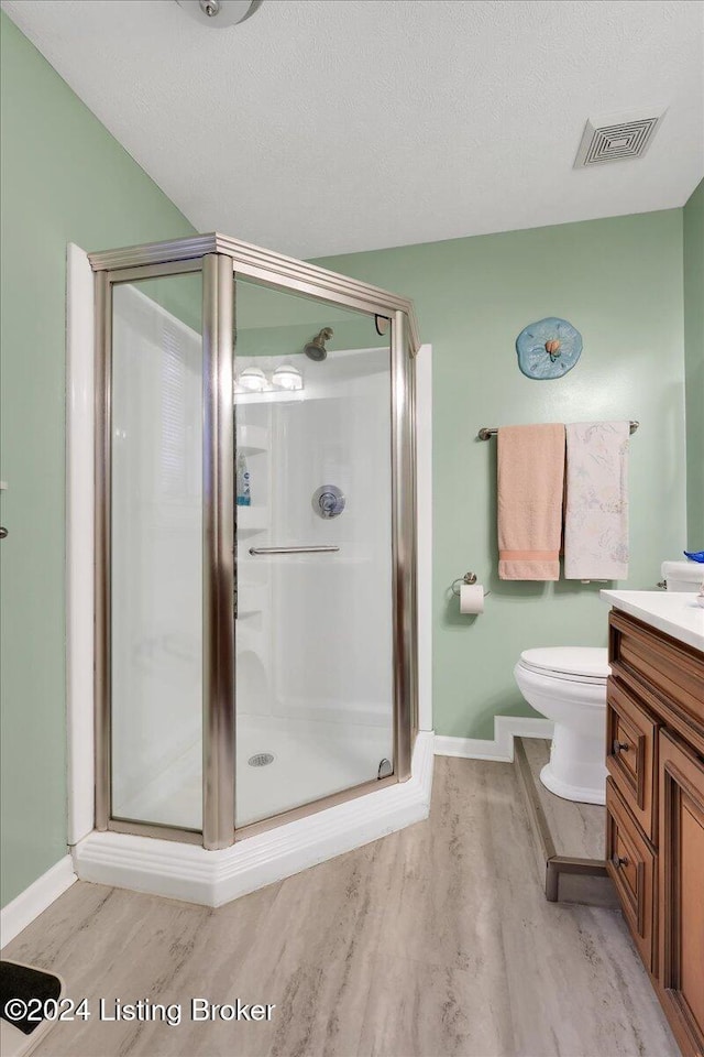 bathroom with vanity, hardwood / wood-style floors, a shower with door, and a textured ceiling