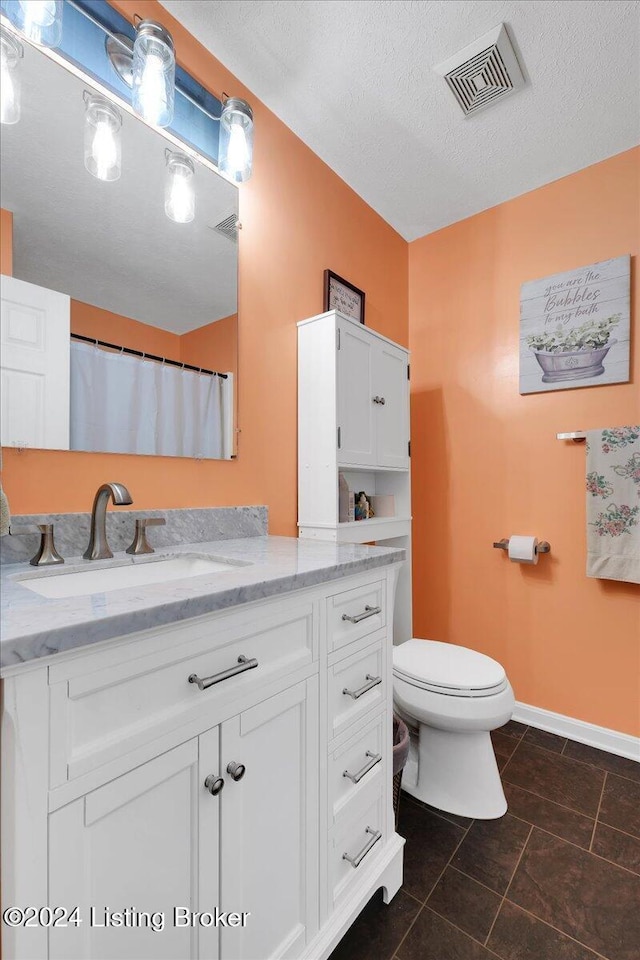 bathroom with vanity, a textured ceiling, and toilet