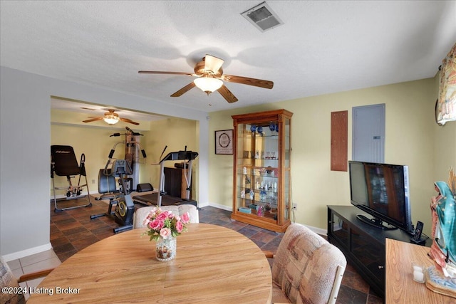 dining space with ceiling fan, electric panel, and a textured ceiling