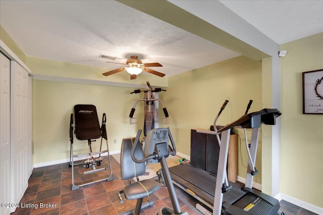 exercise room with ceiling fan and a textured ceiling