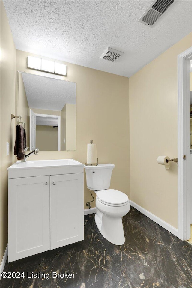 bathroom featuring vanity, a textured ceiling, and toilet