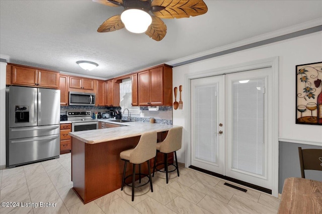 kitchen with a breakfast bar, sink, ceiling fan, kitchen peninsula, and stainless steel appliances