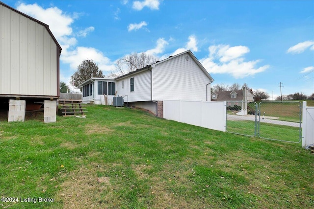 view of property exterior with cooling unit, a sunroom, and a lawn