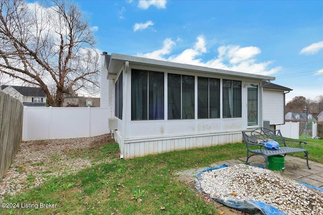 rear view of house with a yard and a sunroom