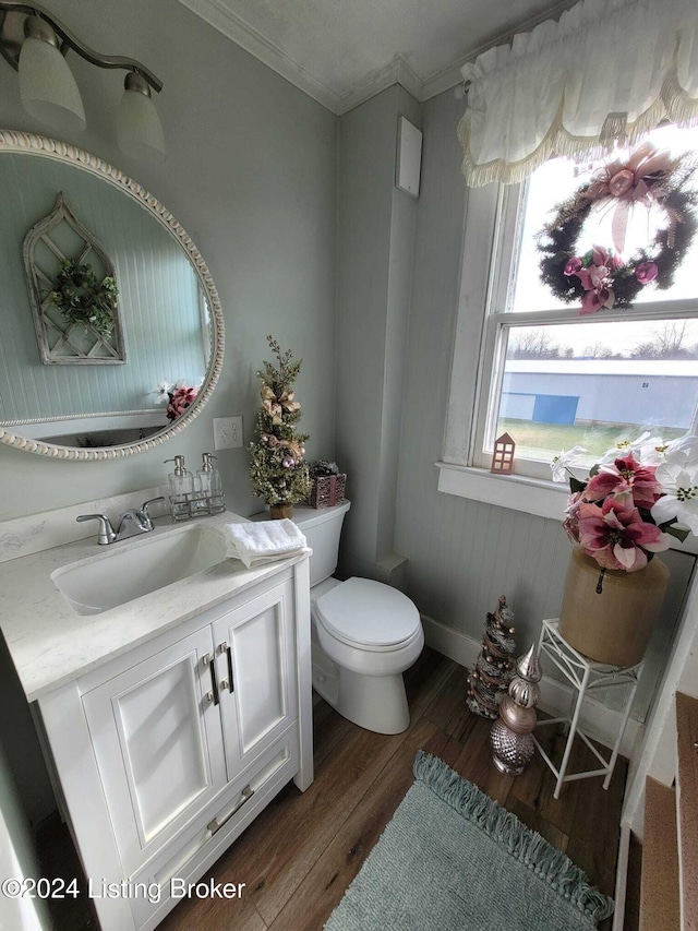 bathroom with crown molding, hardwood / wood-style floors, vanity, and toilet