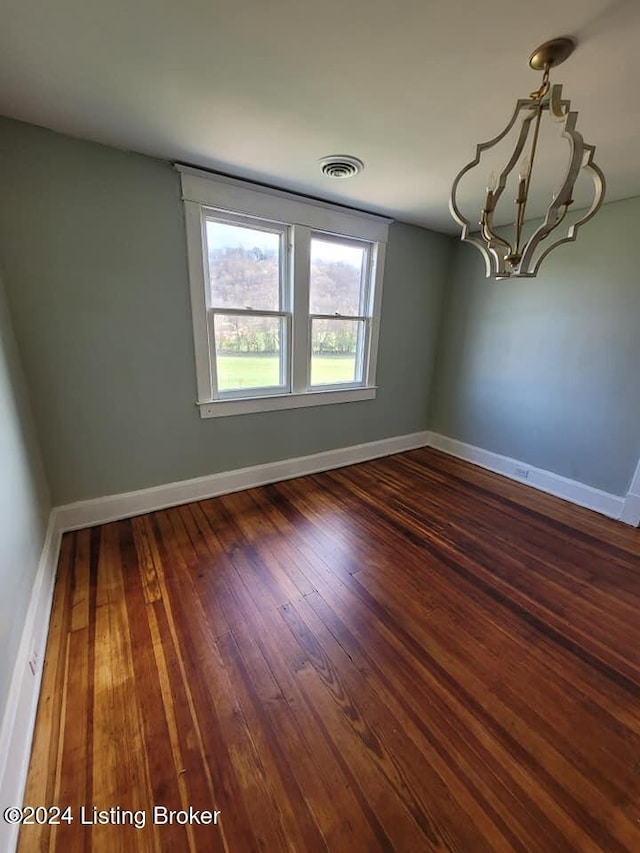 unfurnished room with dark wood-type flooring and an inviting chandelier