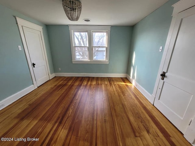 unfurnished room featuring wood-type flooring and a notable chandelier