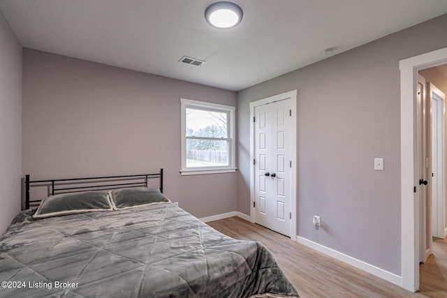 bedroom with light hardwood / wood-style floors and a closet