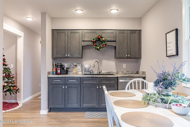 kitchen with gray cabinetry, light stone countertops, dishwasher, sink, and light hardwood / wood-style floors