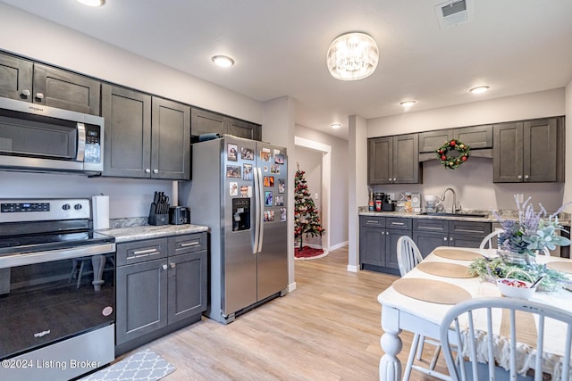 kitchen featuring light stone countertops, sink, light wood-type flooring, and stainless steel appliances