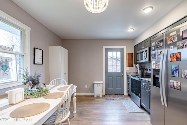 kitchen with gray cabinetry, a healthy amount of sunlight, light wood-type flooring, and appliances with stainless steel finishes