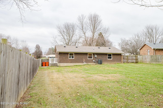 rear view of property featuring central AC unit and a lawn