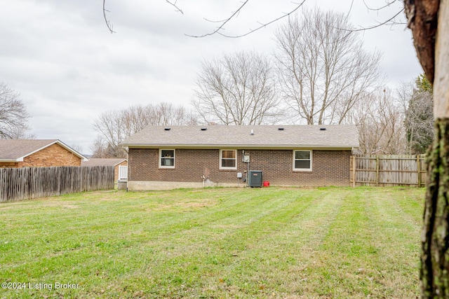 rear view of property with central AC unit and a lawn