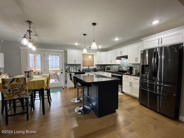 kitchen with stainless steel range with electric stovetop, pendant lighting, white cabinets, and black refrigerator with ice dispenser