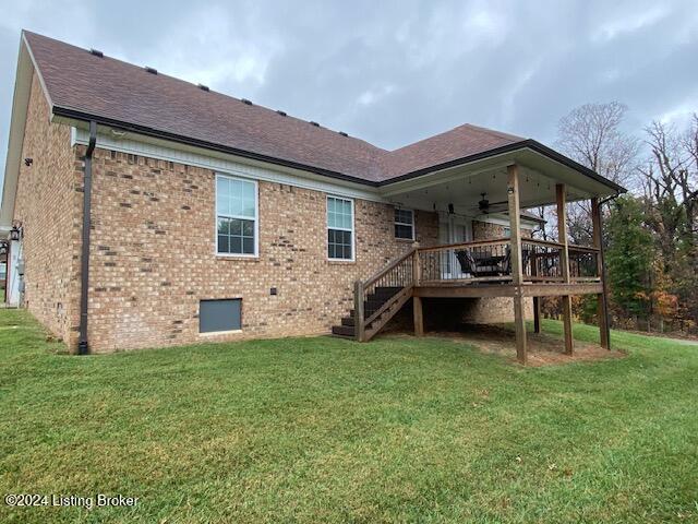 rear view of property featuring a yard, ceiling fan, and a wooden deck