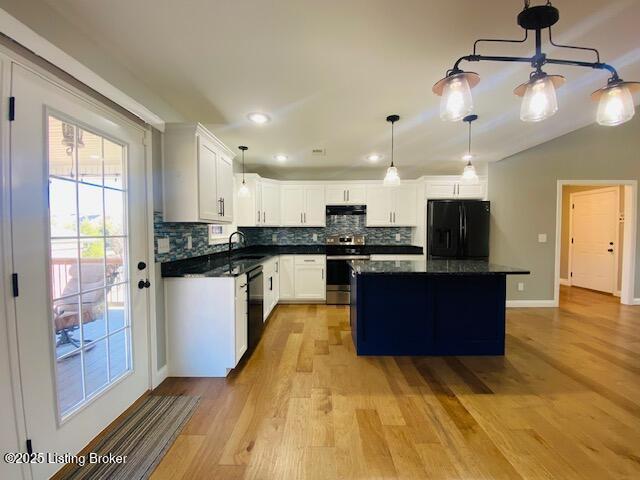 kitchen featuring dark countertops, a kitchen island, decorative backsplash, black appliances, and a sink